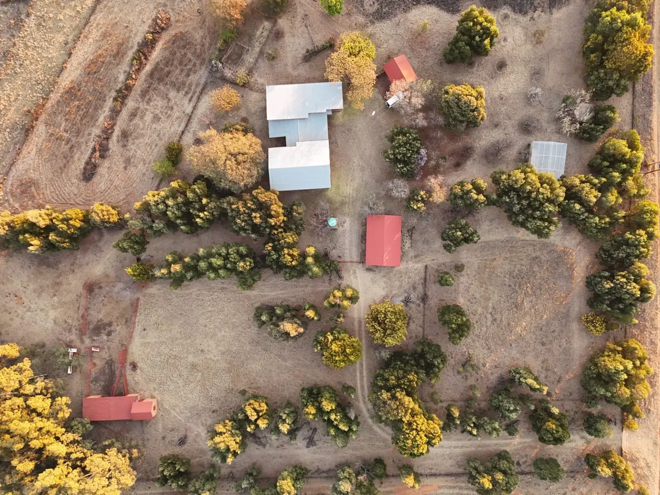 A straight-down aerial view of the property showing buildings, tree lines, internal tracks and boundaries.